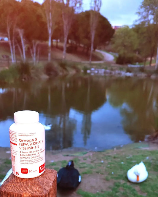 Bote de Omega 3 y vitamina E sobre madera, fondo de lago y patos, suplemento natural
